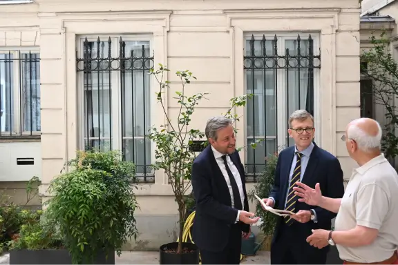 Les associés du cabinet familial Warren & Associés échangent chaleureusement avec un président de conseil syndical dans la cour d'un immeuble en copropriété.