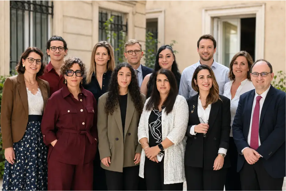 Portrait de l'équipe de l'agence immobilière Warren & Associés Rome réunis dans la cour intérieure en pierre d'un immeuble parisien.
